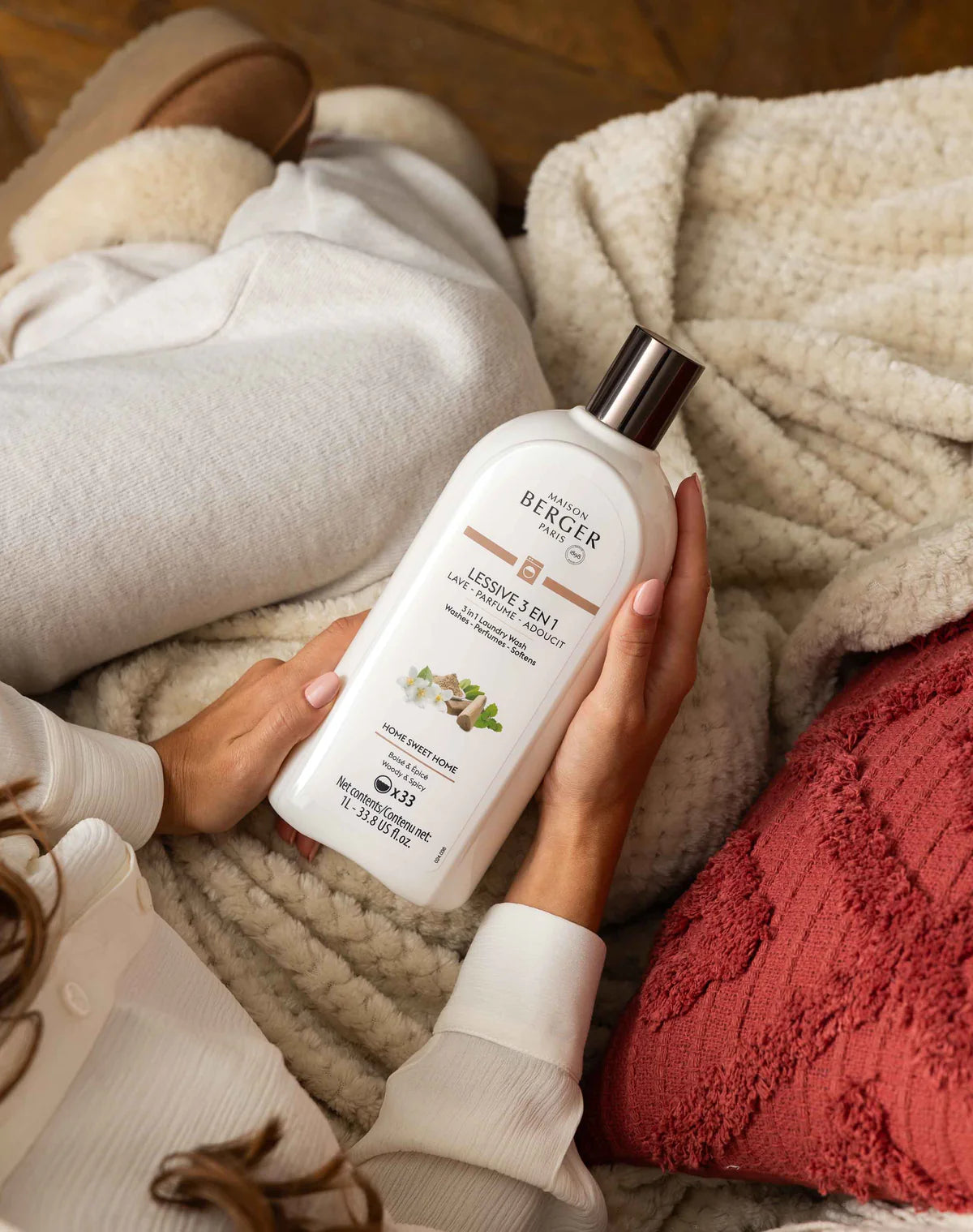 Person holding a bottle of Berger laundry detergent on a cozy blanket