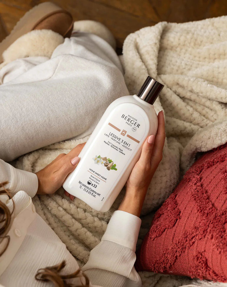 Person holding a bottle of Berger laundry detergent on a cozy blanket